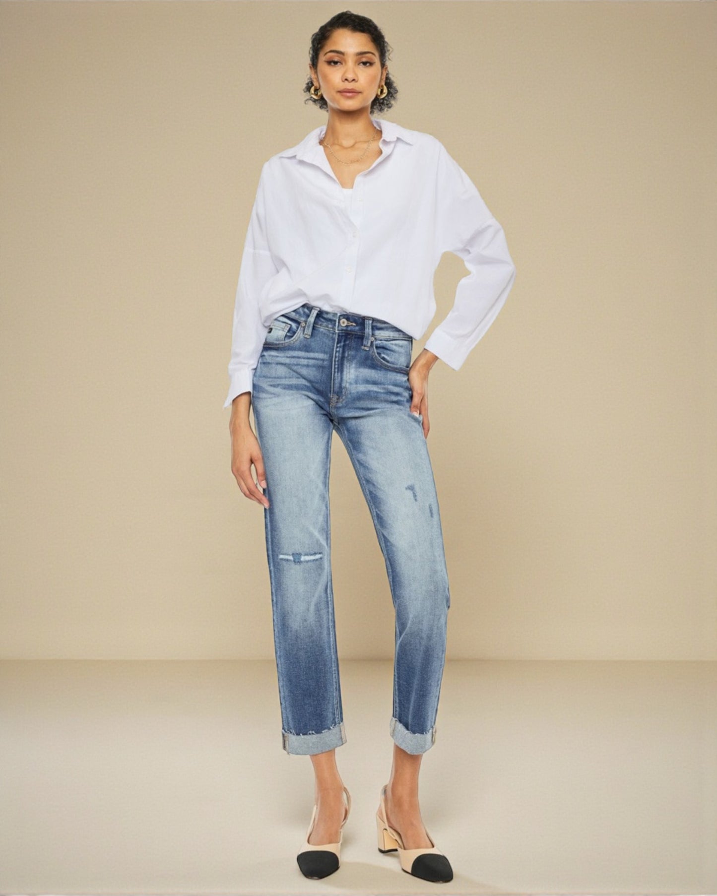Woman wearing a white shirt and blue jeans against a beige background