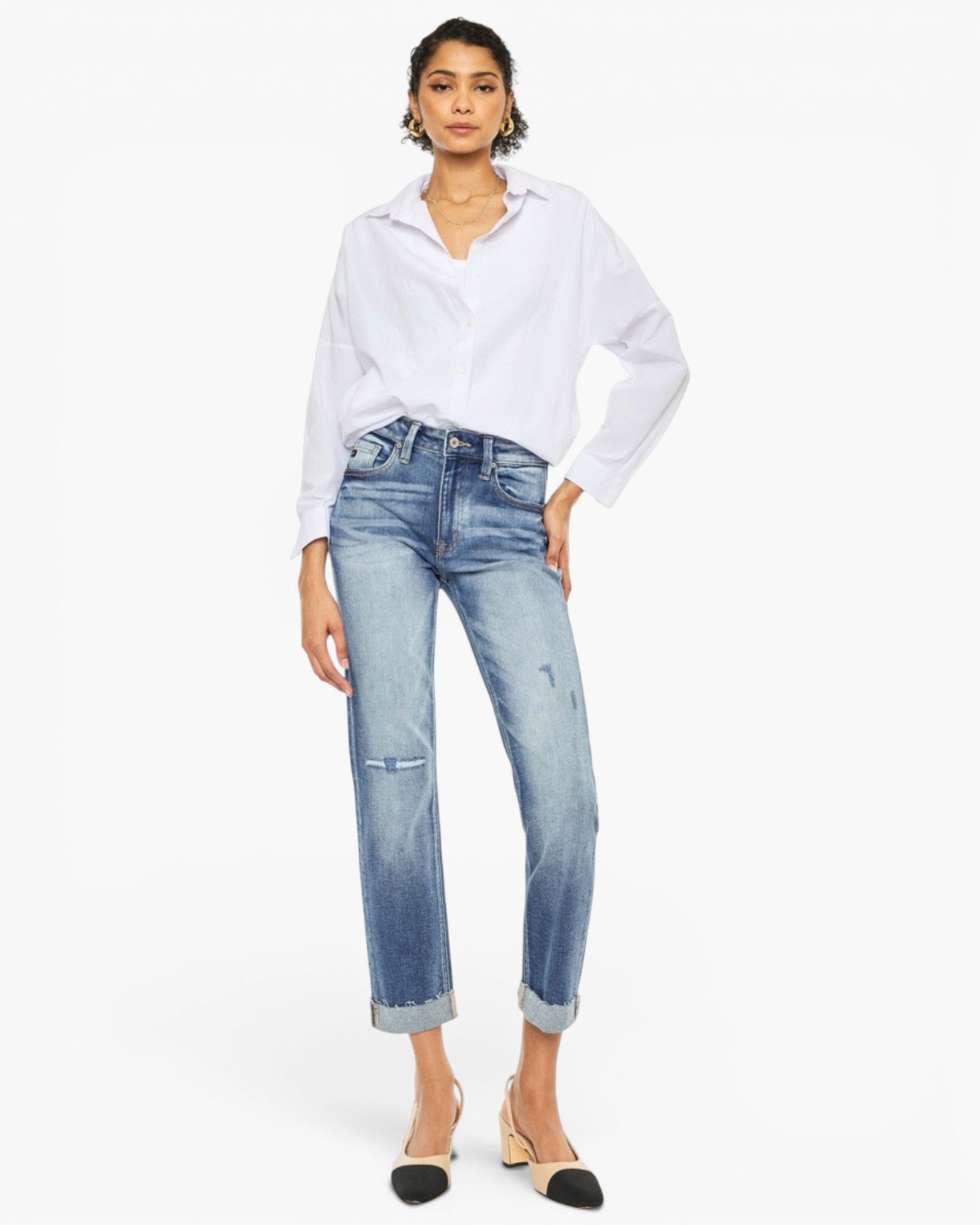 A model wearing a white long-sleeve button-up shirt and light-wash blue cropped jeans with rolled cuffs, paired with black and beige pointed-toe heels, against a plain white studio background.