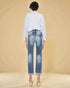 Person wearing blue jeans and a light-colored shirt on a beige background