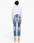 A model shown from the back wearing light-wash blue cropped jeans with a faded wash, a white button-up shirt, and beige wedge sandals against a plain white background.