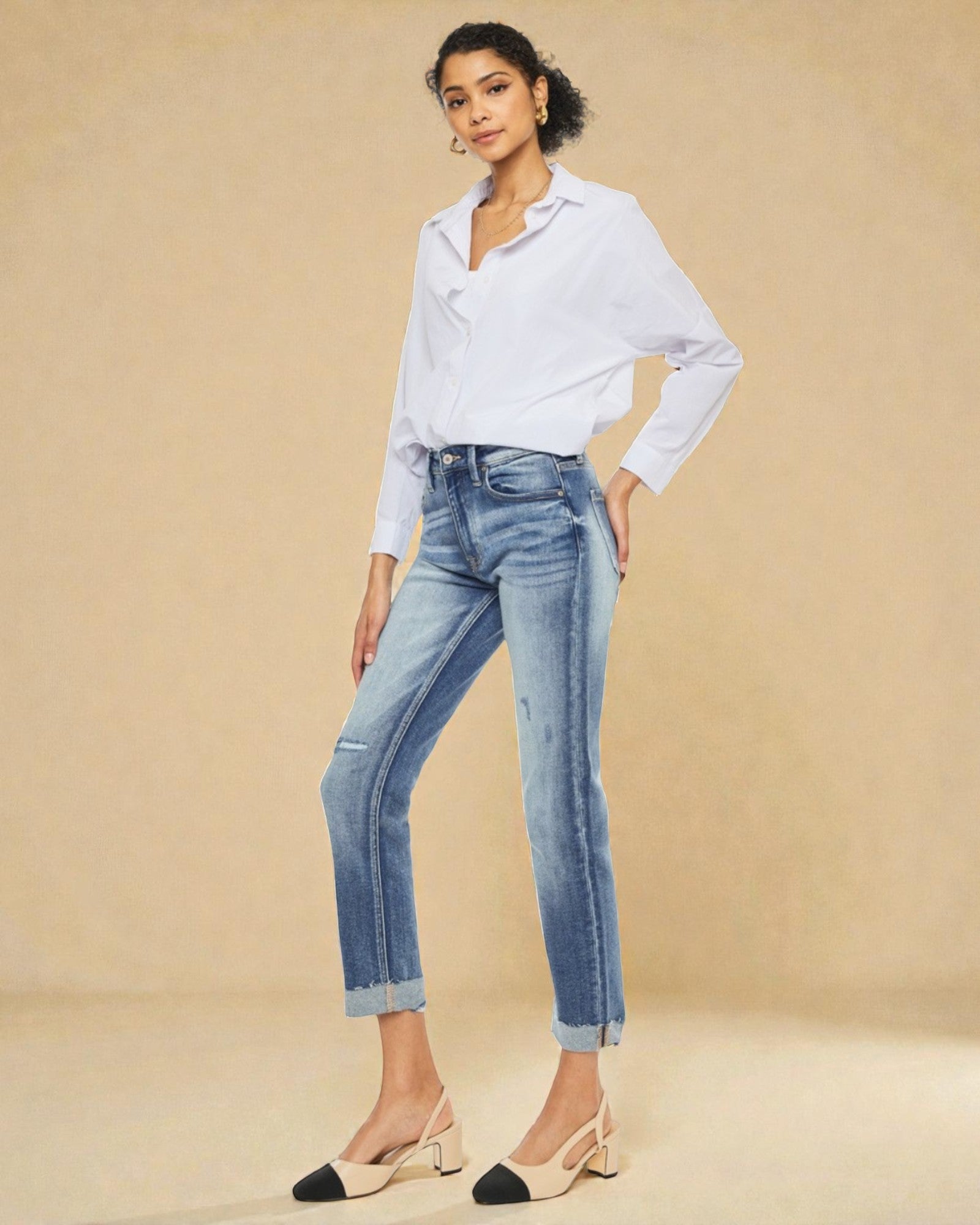 Woman wearing a white shirt and blue jeans against a beige background