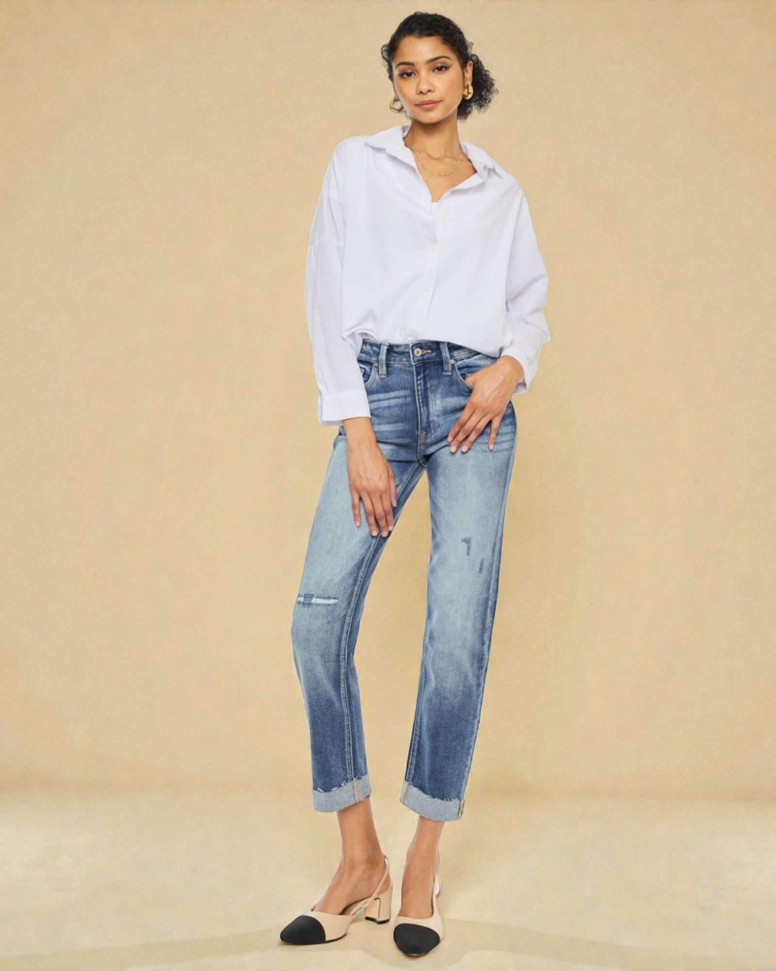 Woman wearing a white shirt and blue jeans against a beige background