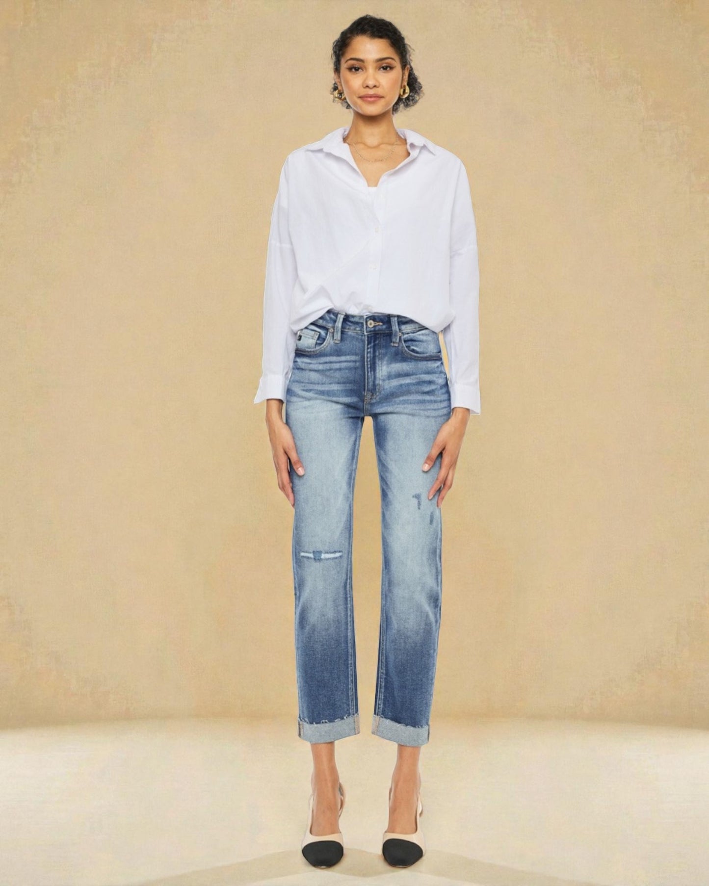 Woman wearing a light blue shirt and jeans against a beige background