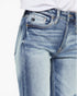 Close-up of a person wearing light blue denim jeans with a white shirt partially visible at the waist, against a plain white background.