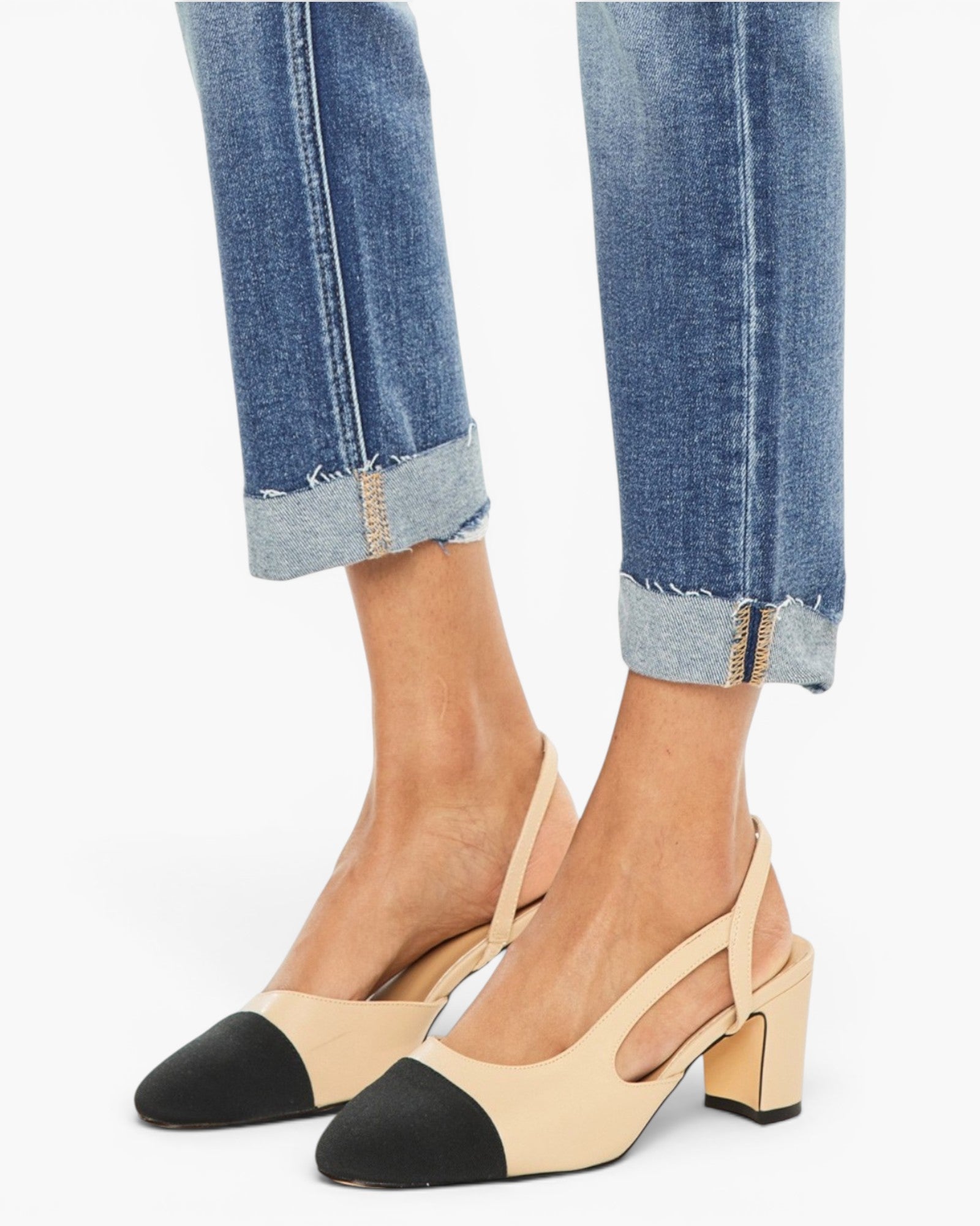 A pair of women's slingback block-heel pumps in beige and black, shown on a model wearing cuffed blue jeans against a plain white background.