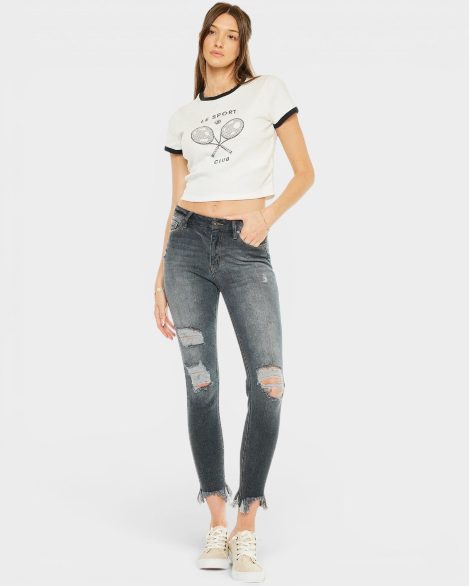 Woman wearing a white t-shirt with a graphic design and distressed jeans on a white background