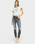 Woman wearing a white t-shirt with a graphic design and distressed jeans on a white background