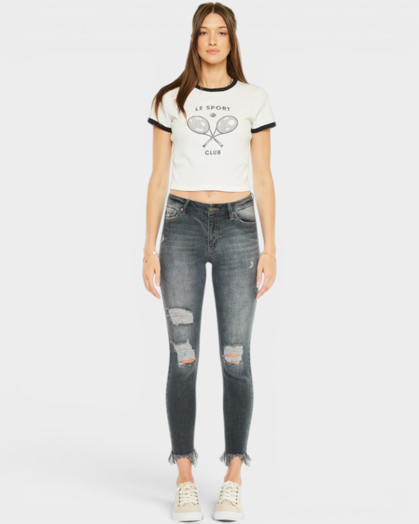 Woman wearing a white t-shirt with a graphic design and ripped jeans on a white background