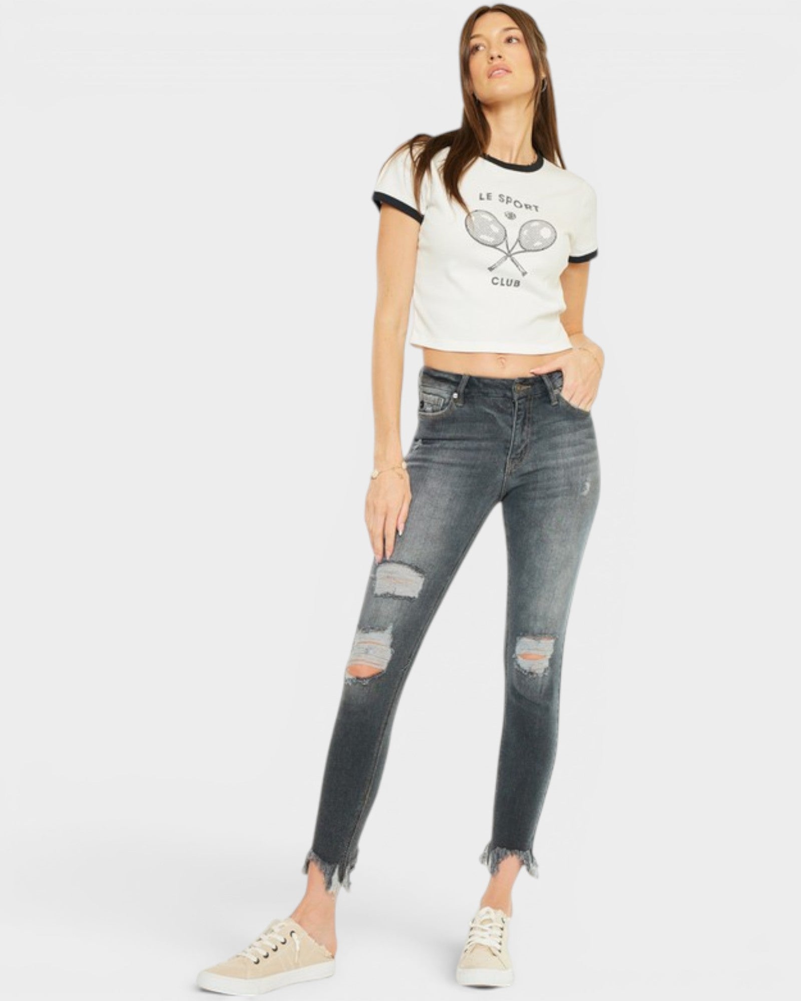 Woman wearing a white graphic t-shirt and distressed jeans on a white background
