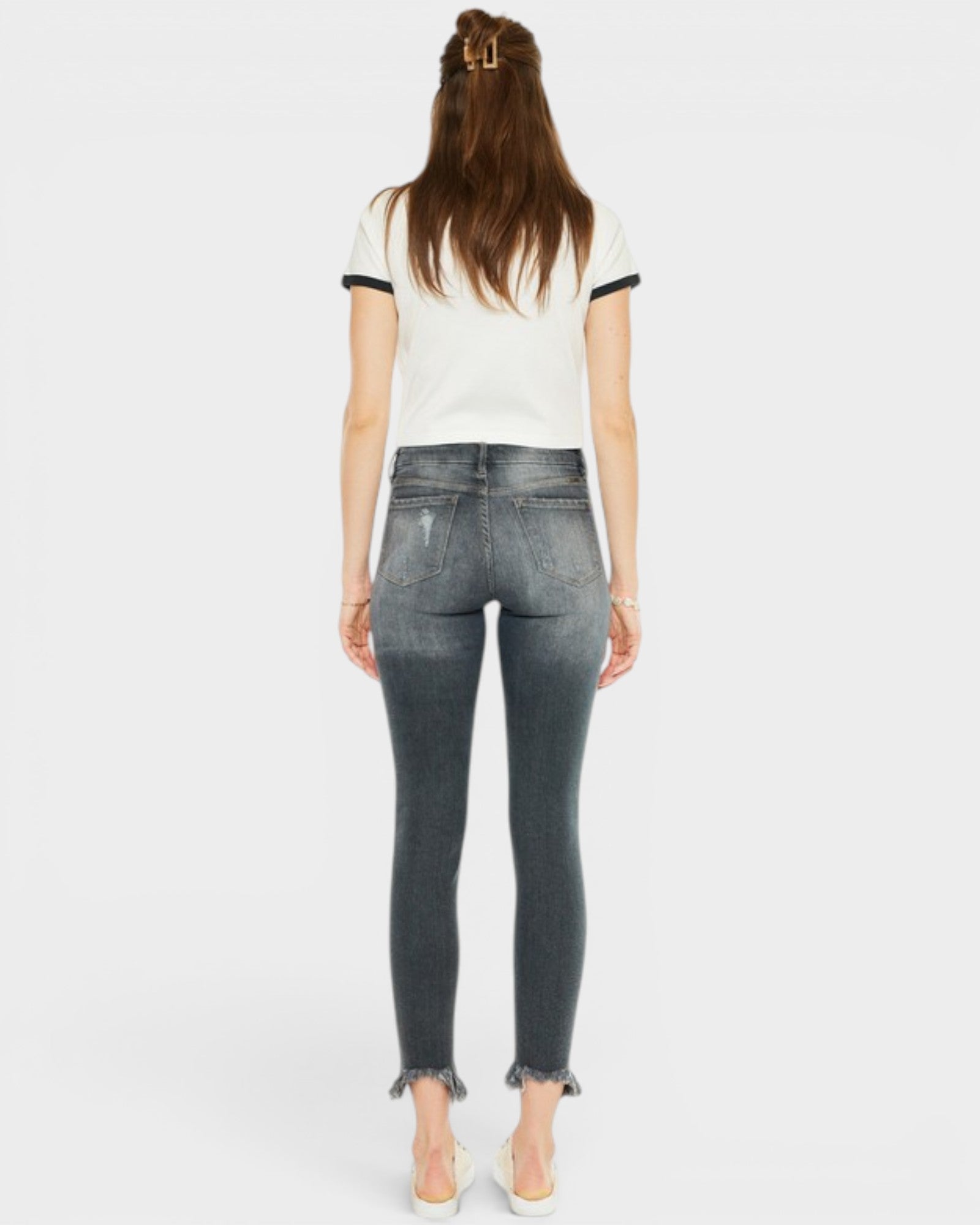 Person wearing a white t-shirt with black trim and dark jeans on a white background