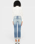 Person wearing light blue jeans and a white blouse on a plain background