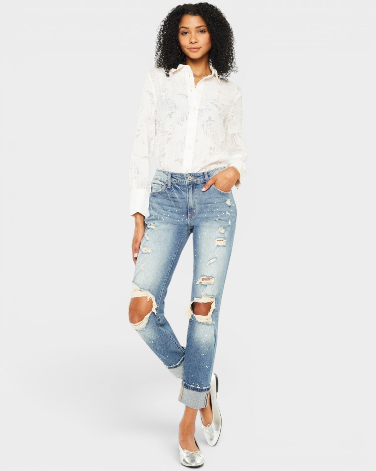 Woman wearing a white lace top and ripped blue jeans on a white background
