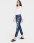 Woman wearing a white shirt and blue distressed jeans on a white background