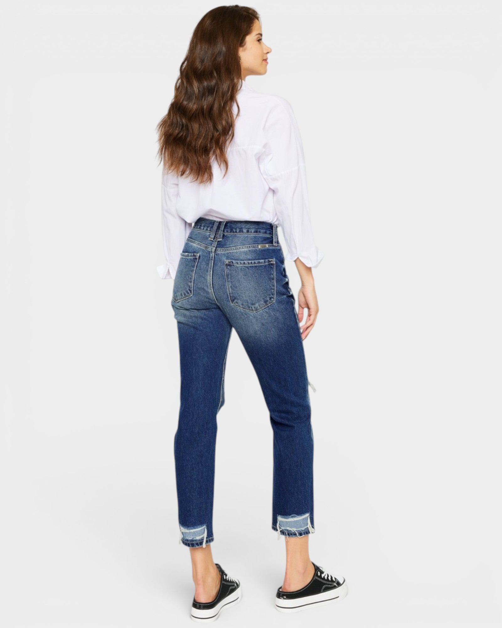 Woman wearing blue jeans and a white shirt on a white background