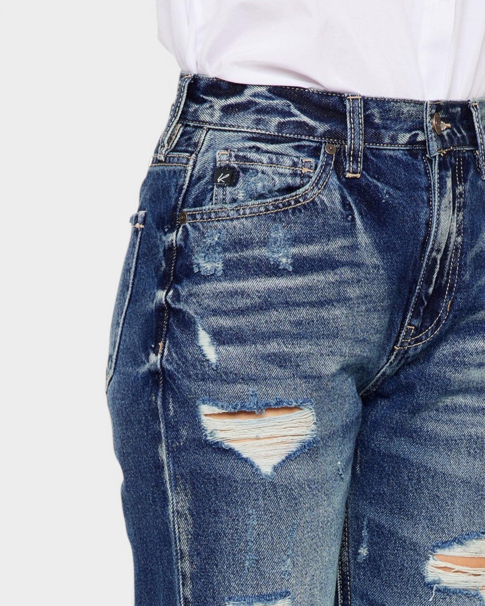 Close-up of distressed blue jeans on a white background