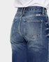 Close-up of blue jeans with a white shirt underneath on a light gray background