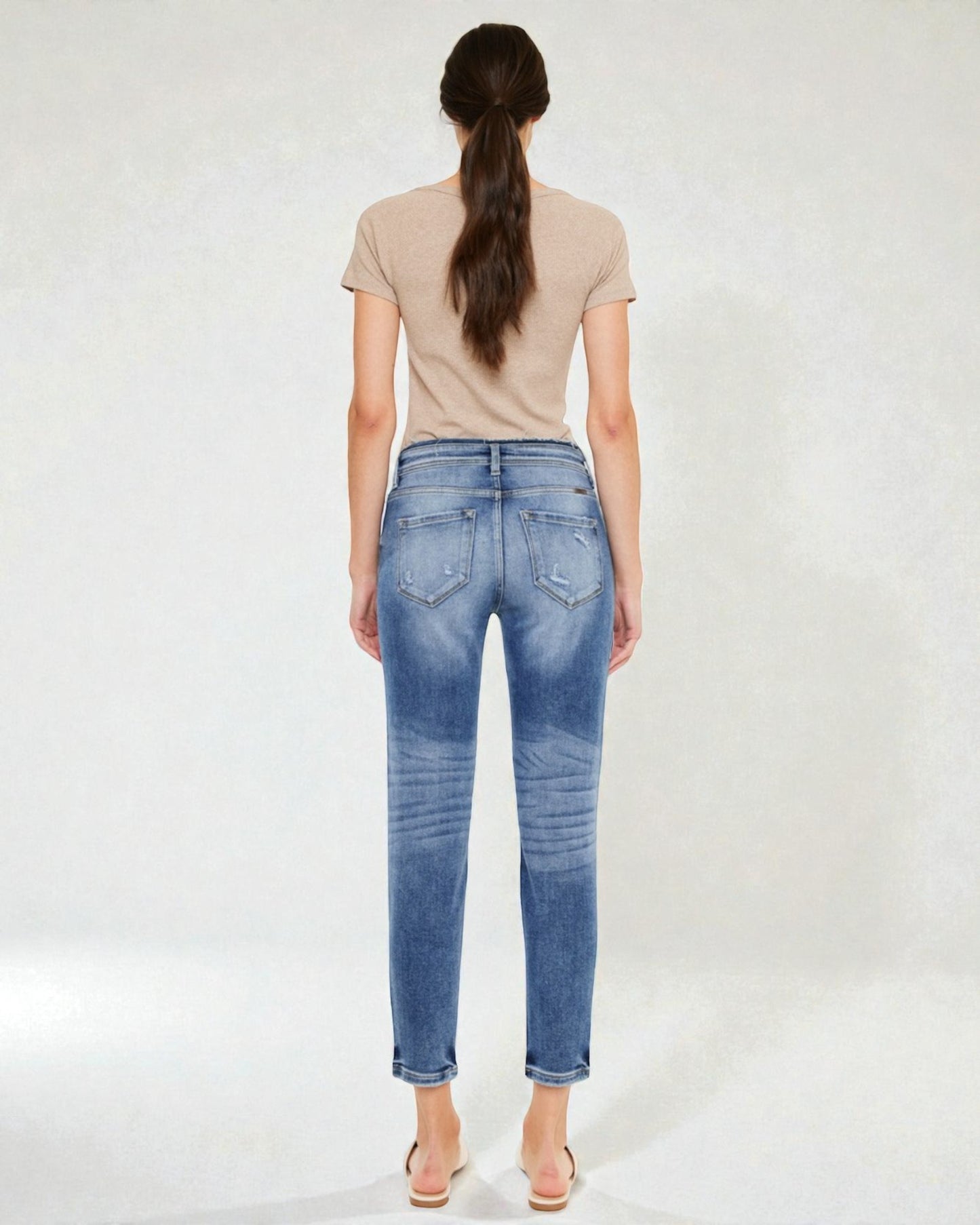 Woman wearing blue jeans and a beige top on a white background
