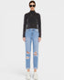 Person wearing a black turtleneck and light blue ripped jeans on a white background