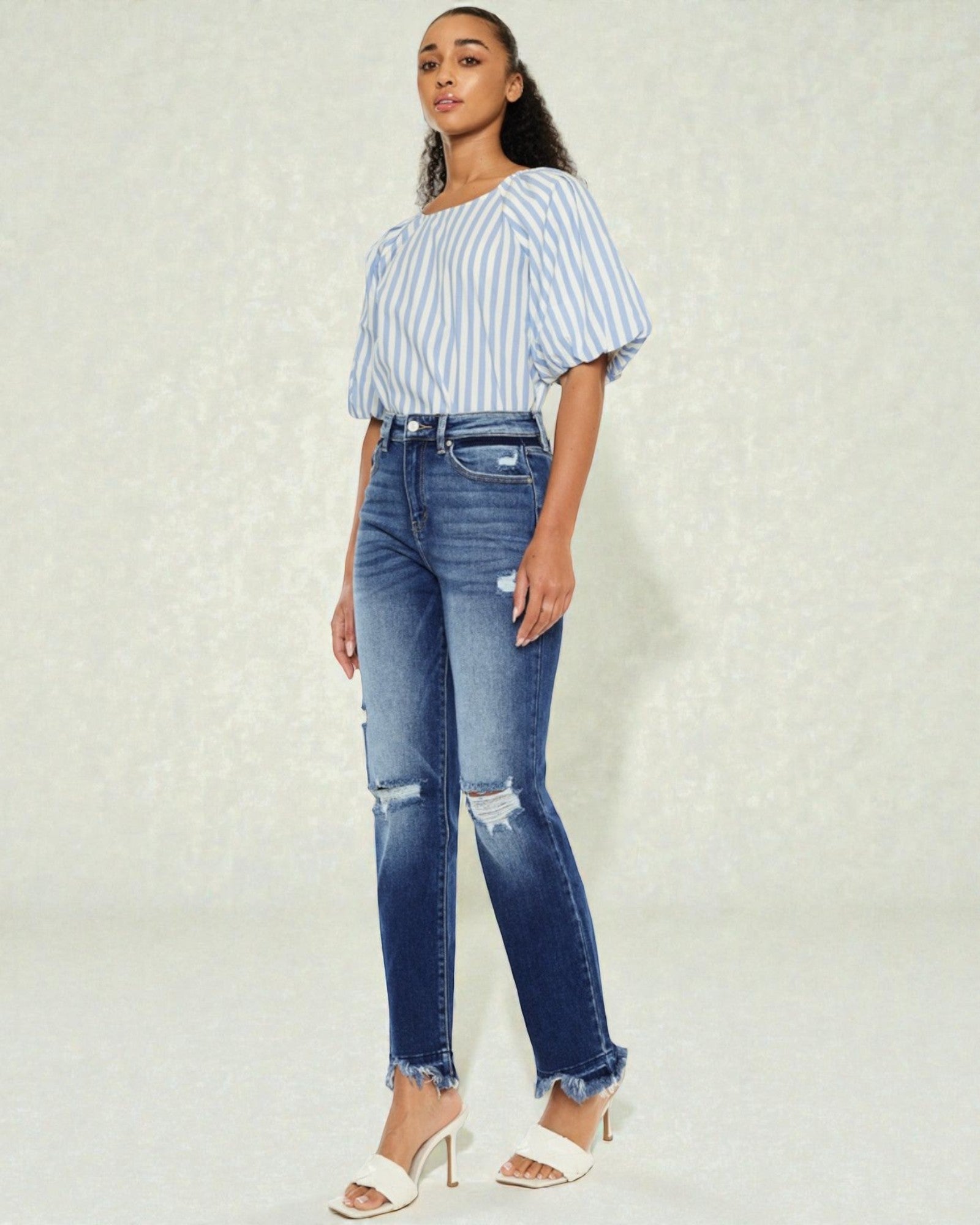 Woman wearing a striped top and blue jeans on a light background