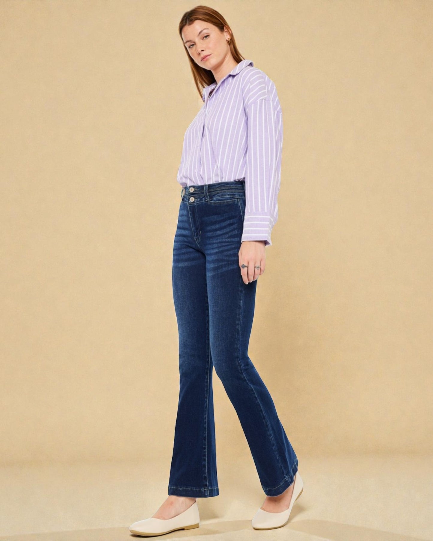 Woman wearing a striped shirt and blue jeans against a beige background