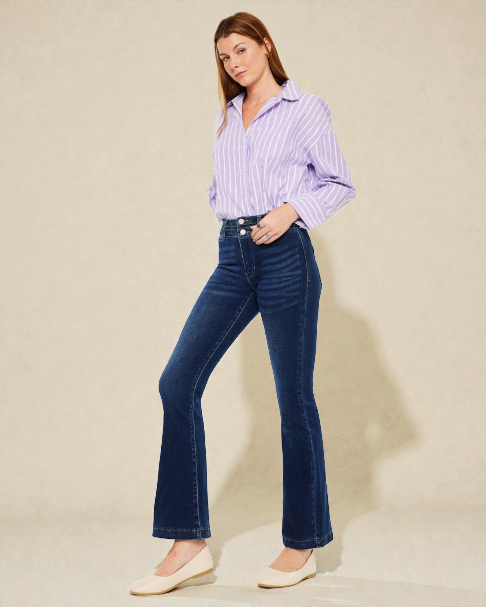Woman wearing a striped shirt and blue jeans on a beige background