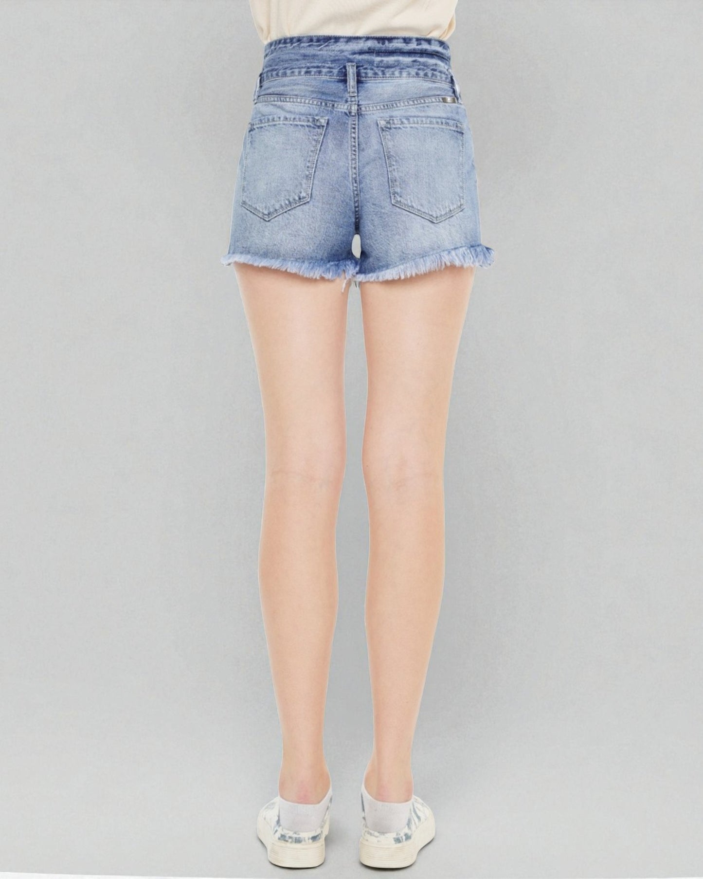 Light blue denim shorts worn by a person on a gray background