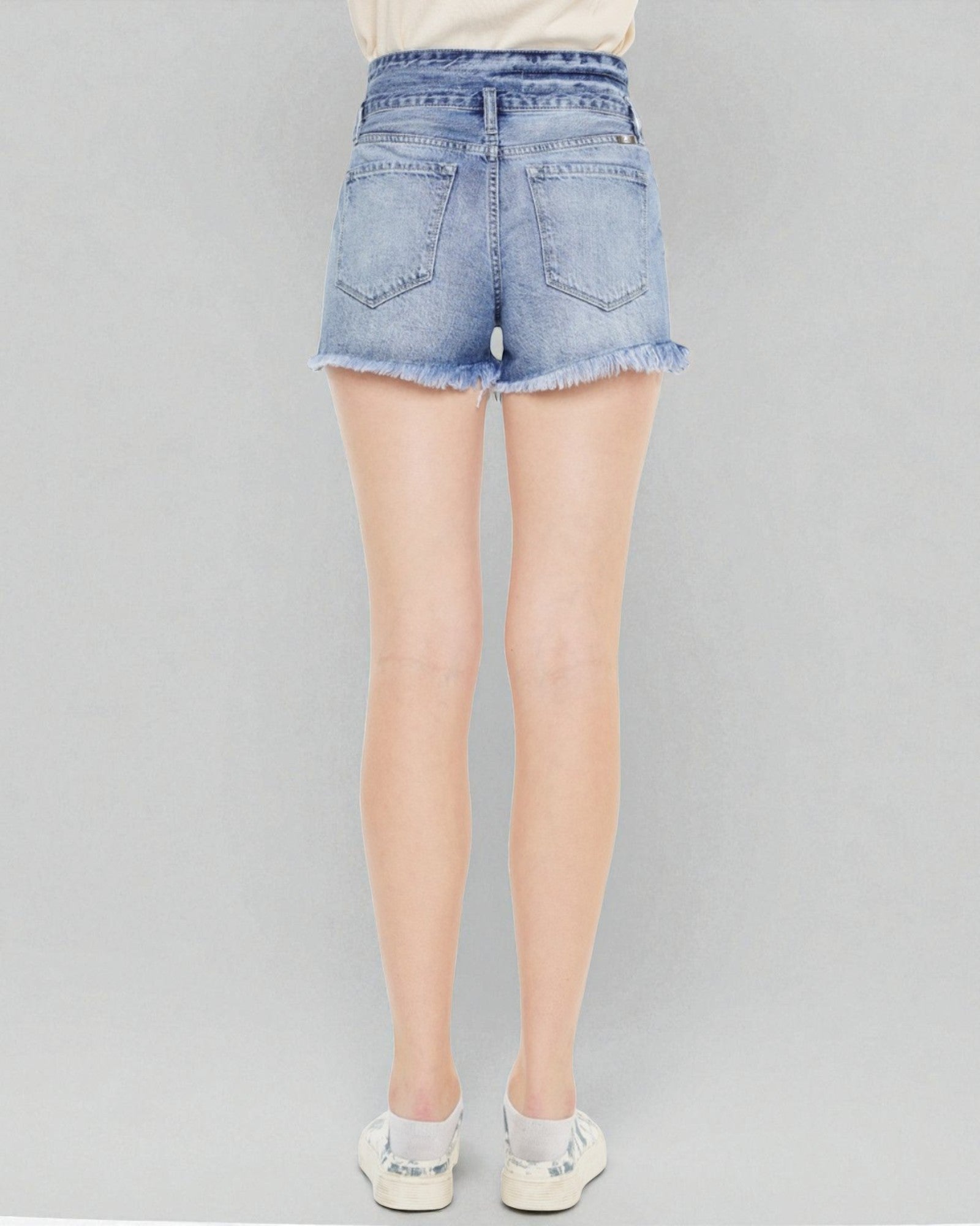 Light blue denim shorts worn by a person on a gray background