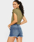 Woman wearing an olive green top and denim shorts on a white background