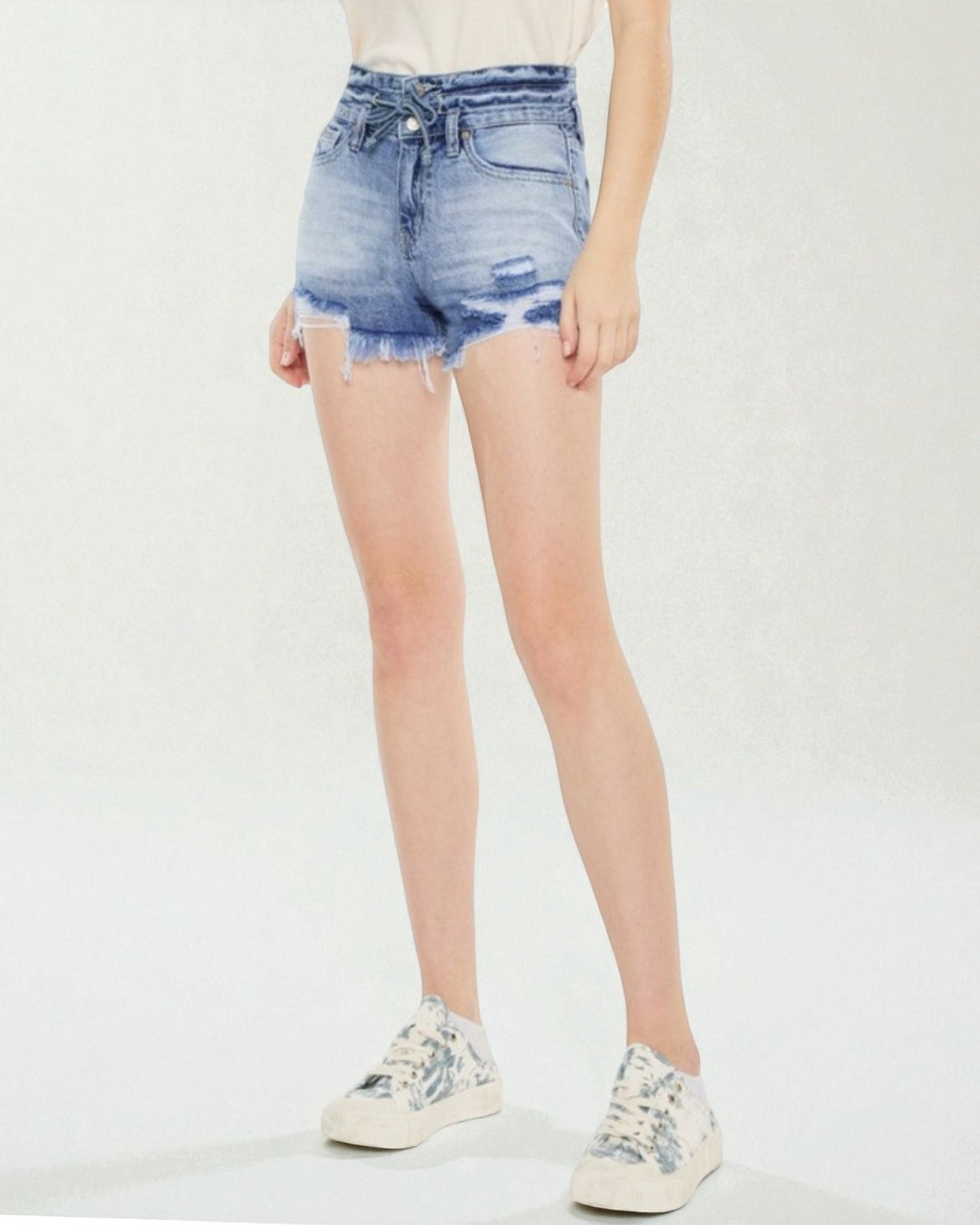 Person wearing distressed denim shorts on a white background
