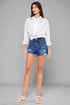 Woman wearing a white shirt and blue denim shorts on a gray background