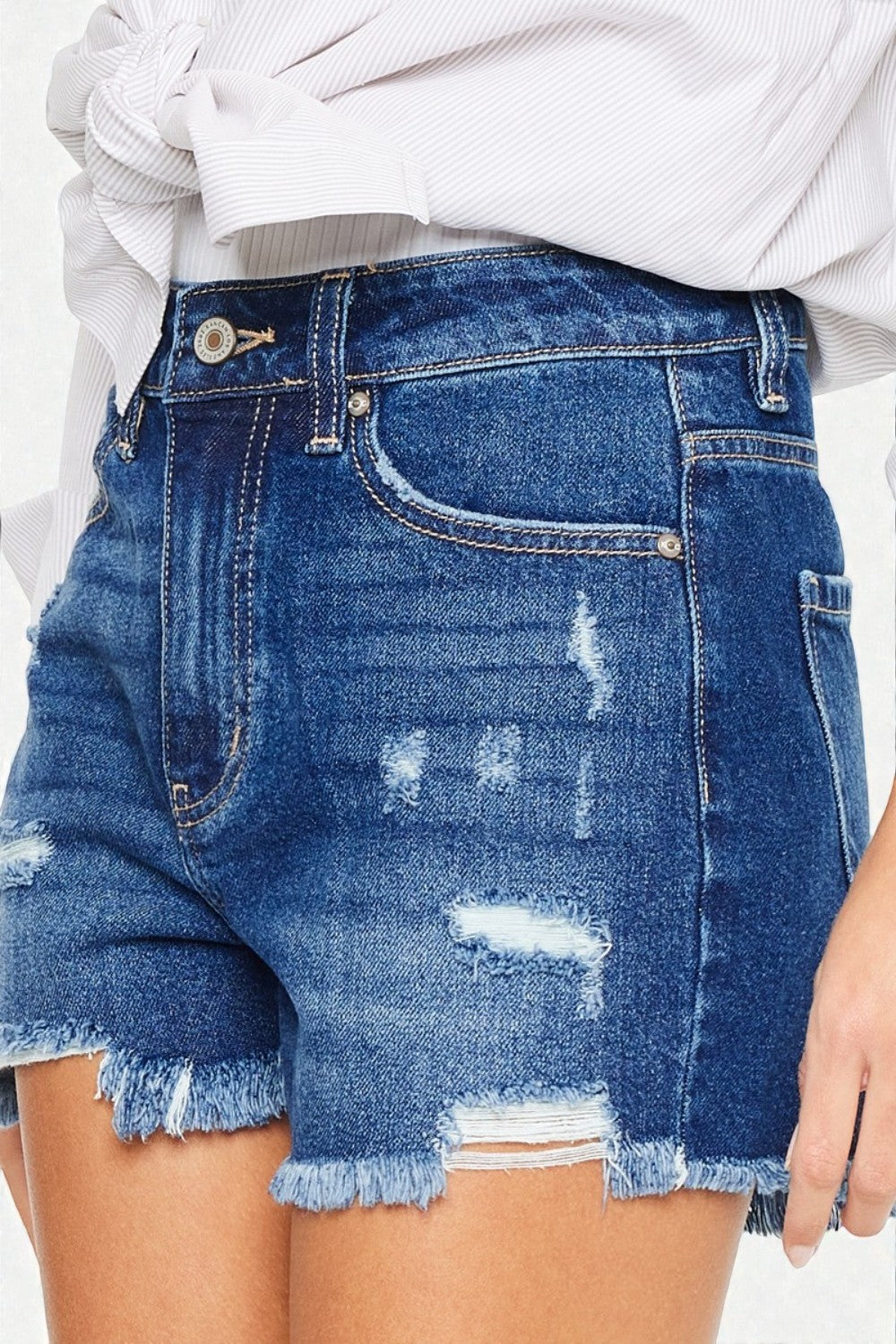Blue denim shorts with frayed edges worn by a person.