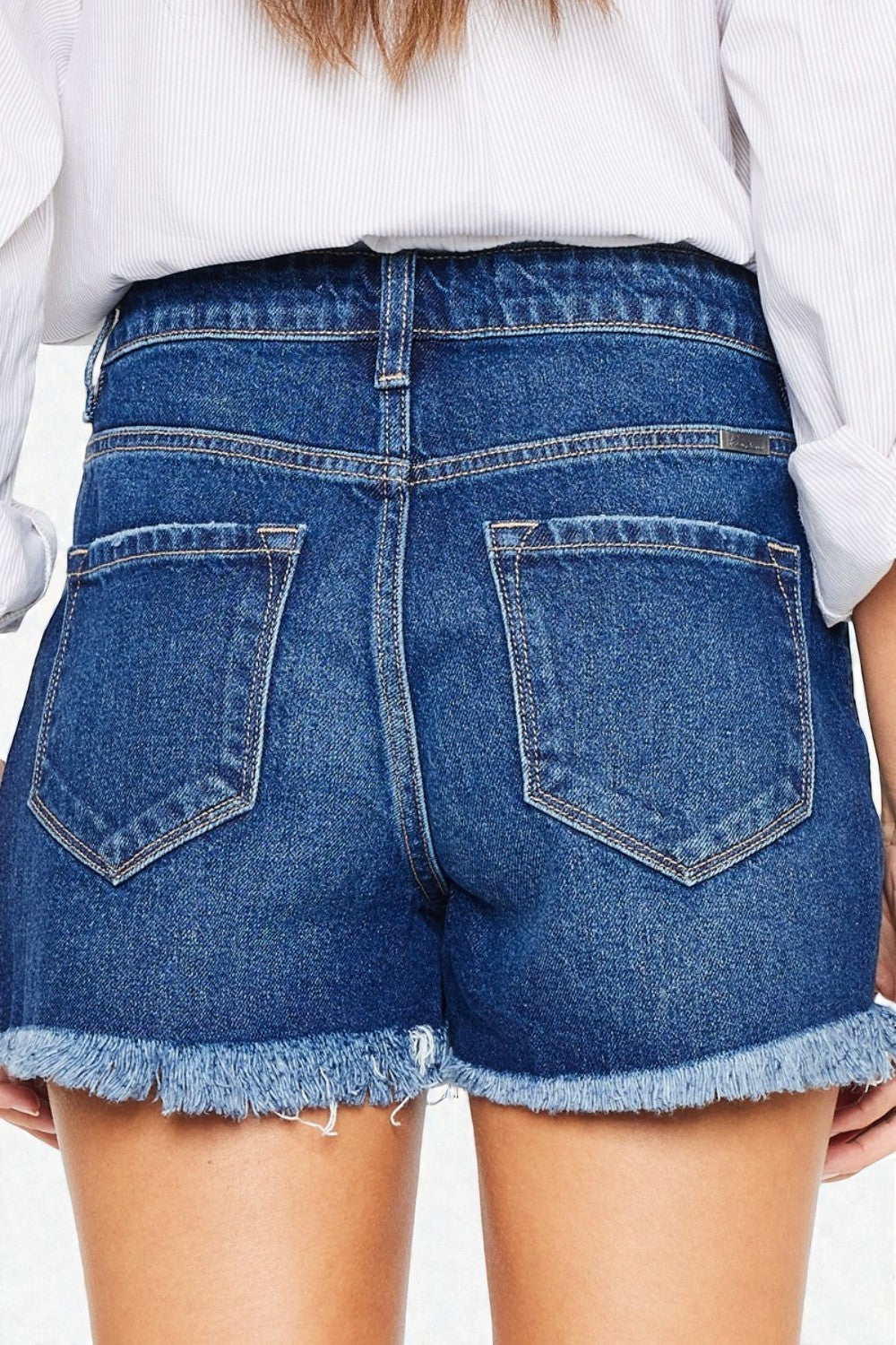 Blue denim shorts with frayed hem on a plain background