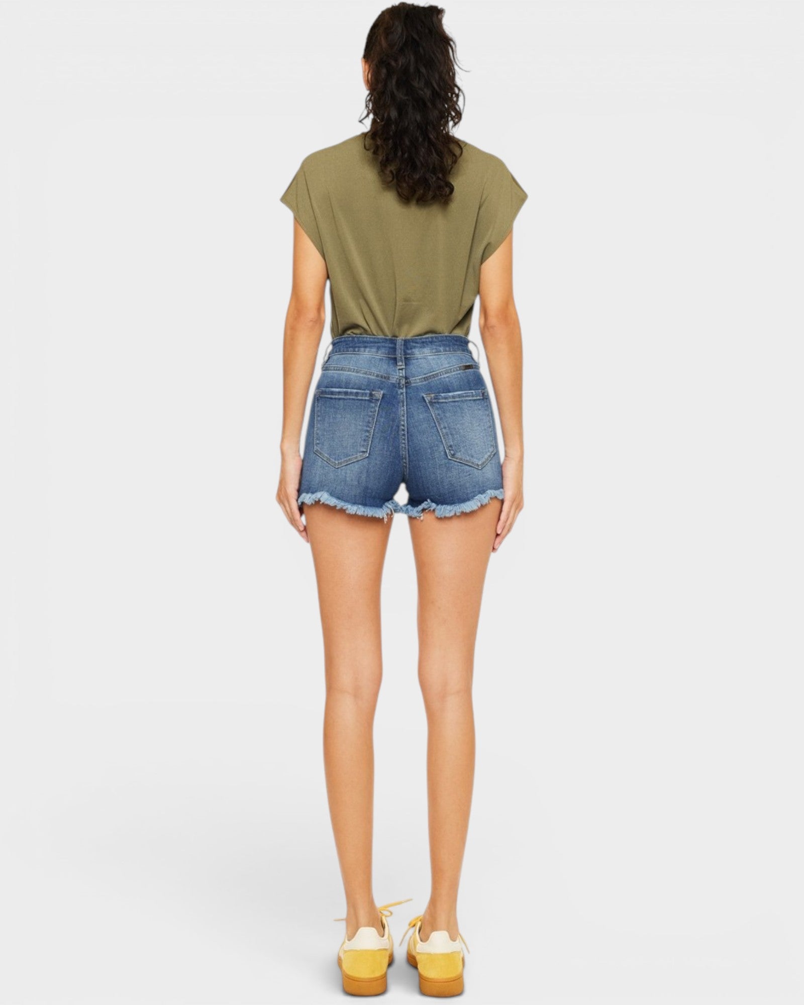 Person wearing a green t-shirt and denim shorts on a white background
