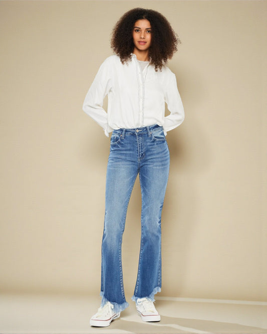 Woman wearing a white blouse and blue jeans against a beige background