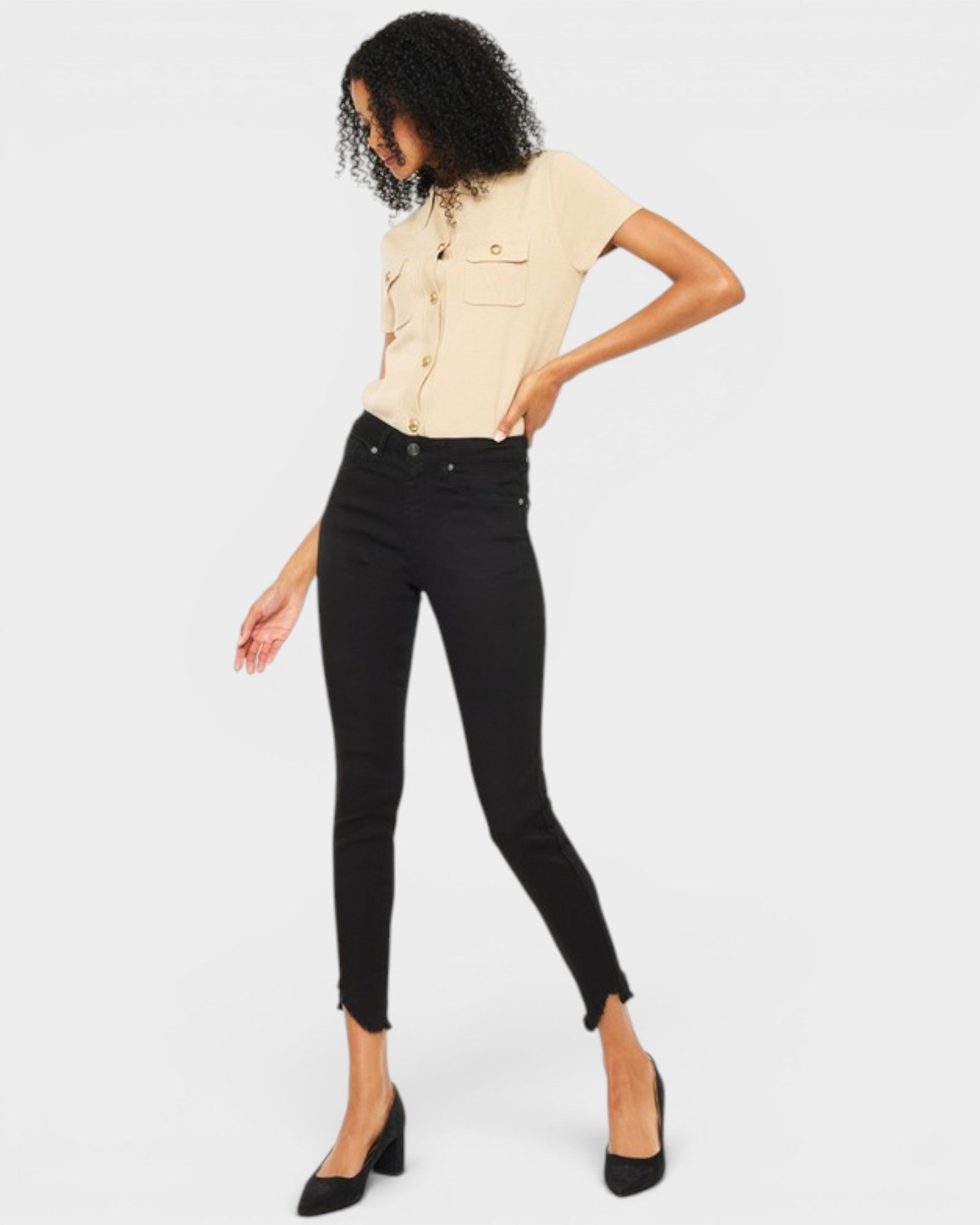 Woman wearing a beige top and black jeans on a white background
