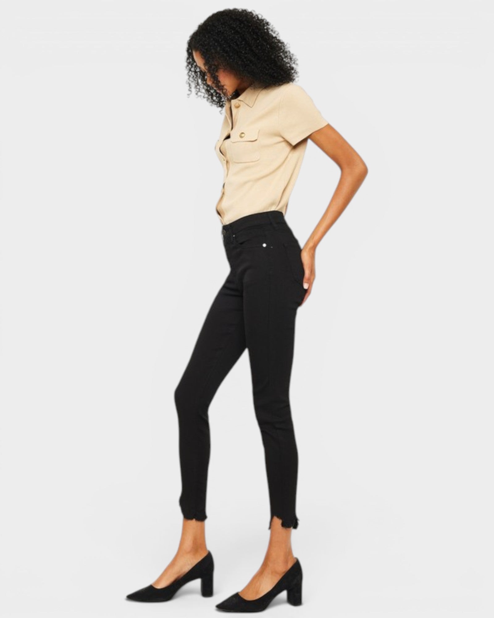 Woman wearing a beige shirt and black jeans on a white background