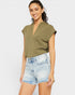 Woman wearing an olive green top and light blue denim shorts on a white background