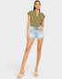 Woman wearing a green top and denim shorts on a white background