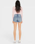 Person wearing denim shorts and a pink top on a white background