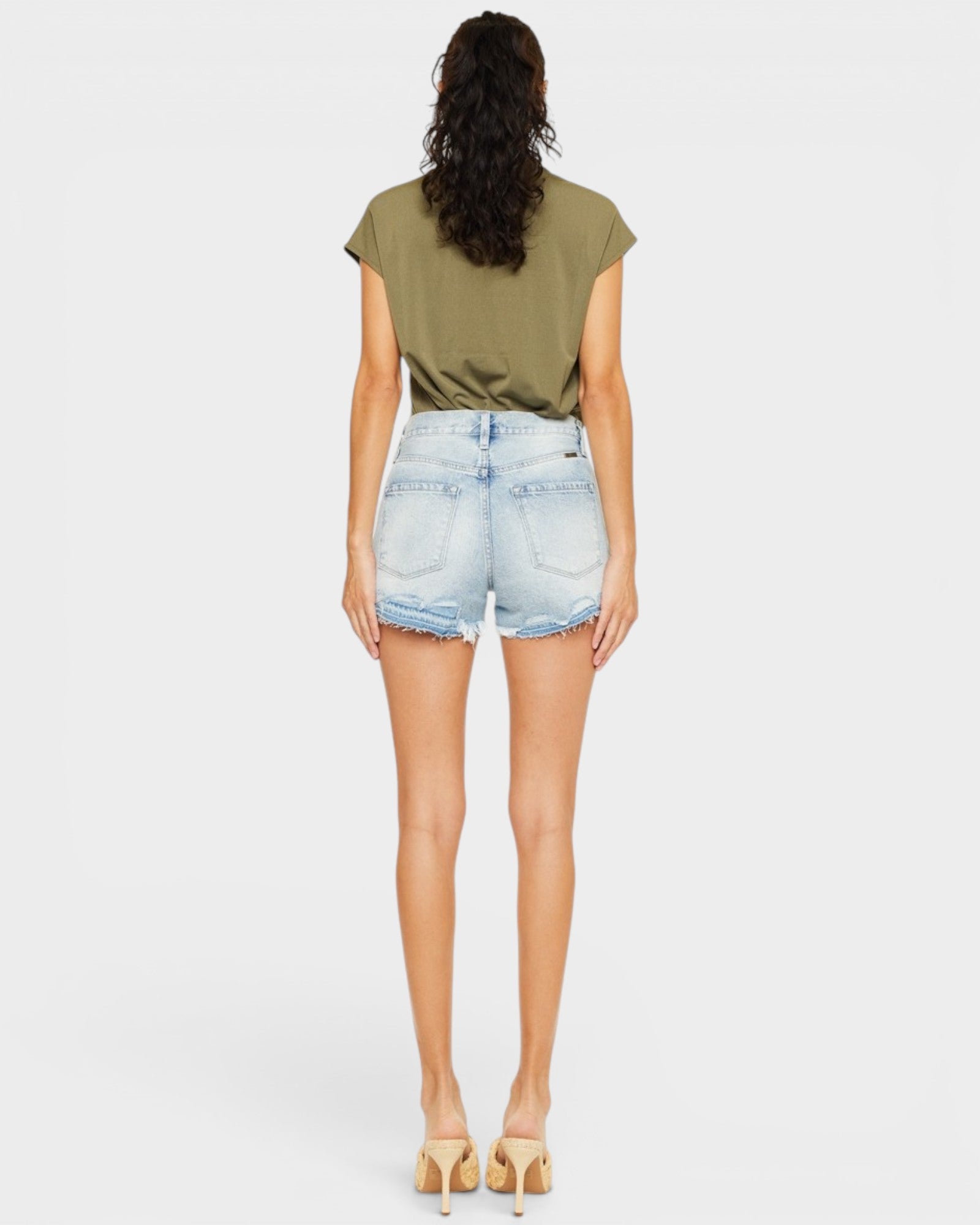 Woman wearing a green t-shirt and light blue denim shorts on a white background