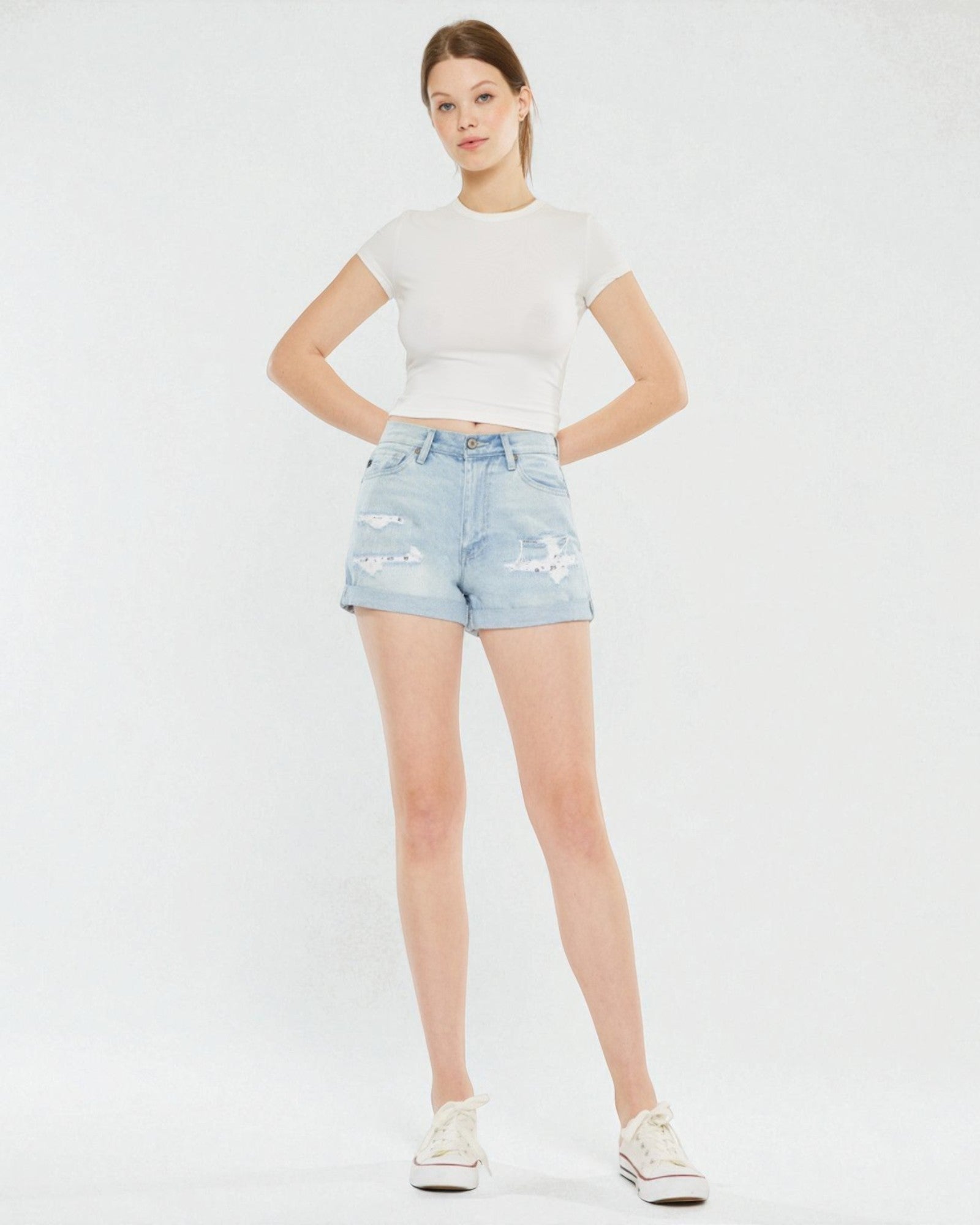 Woman wearing a white t-shirt and light blue denim shorts on a white background