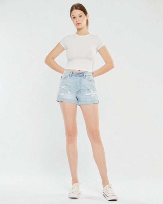 Woman wearing a white t-shirt and light blue denim shorts on a white background