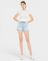 Woman wearing a white t-shirt and light blue denim shorts on a plain background