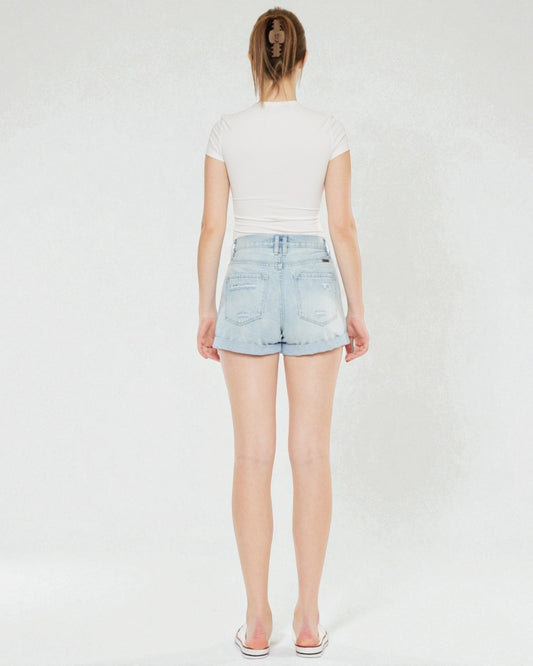 Person wearing a white top and light blue denim shorts on a plain background