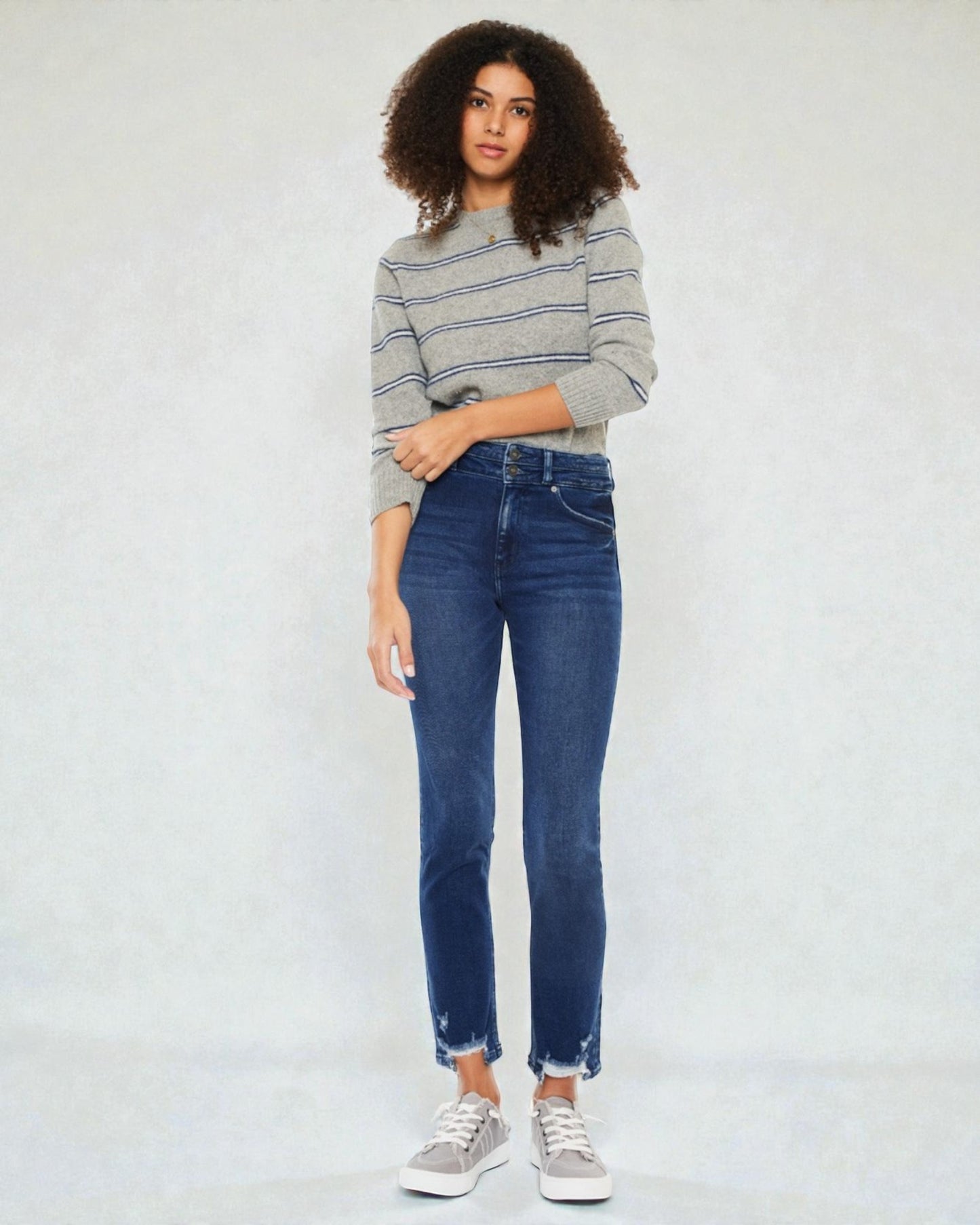 Person wearing a striped sweater and blue jeans against a white background