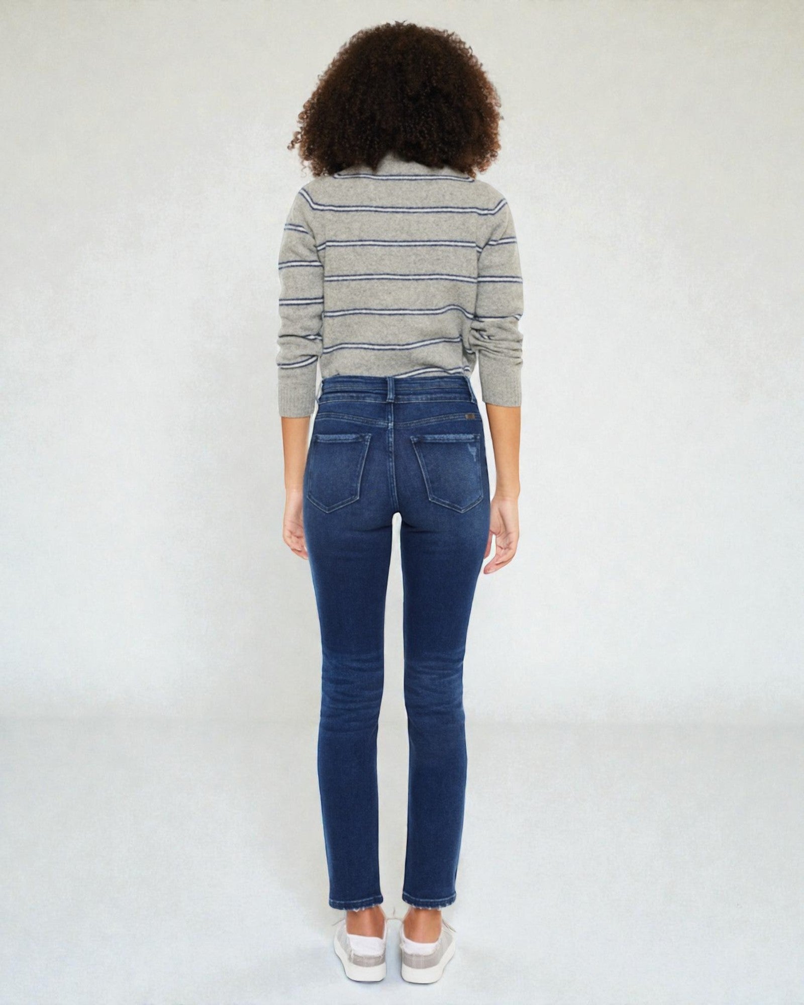 Person wearing a striped sweater and blue jeans against a white background