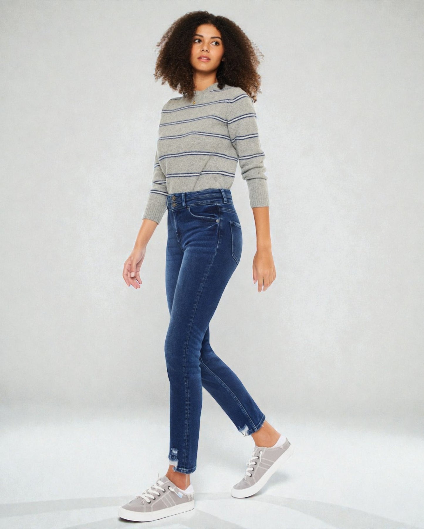 Woman wearing a striped sweater and blue jeans on a white background