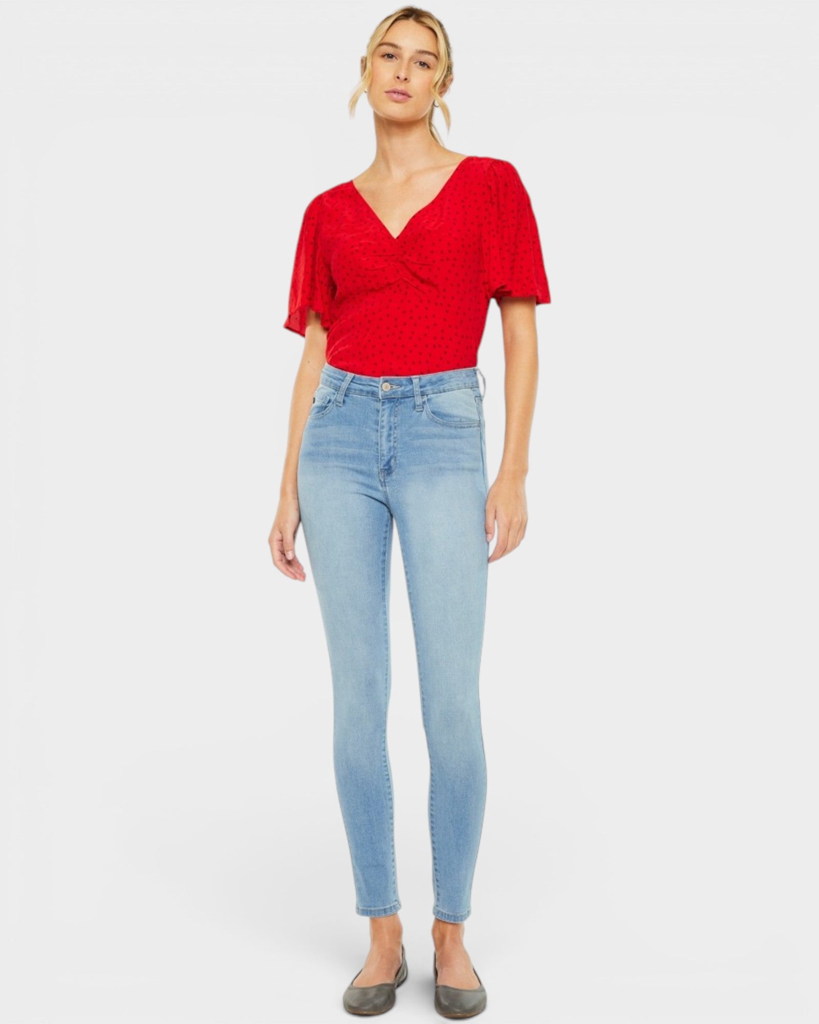 Woman wearing a red top and light blue jeans on a white background