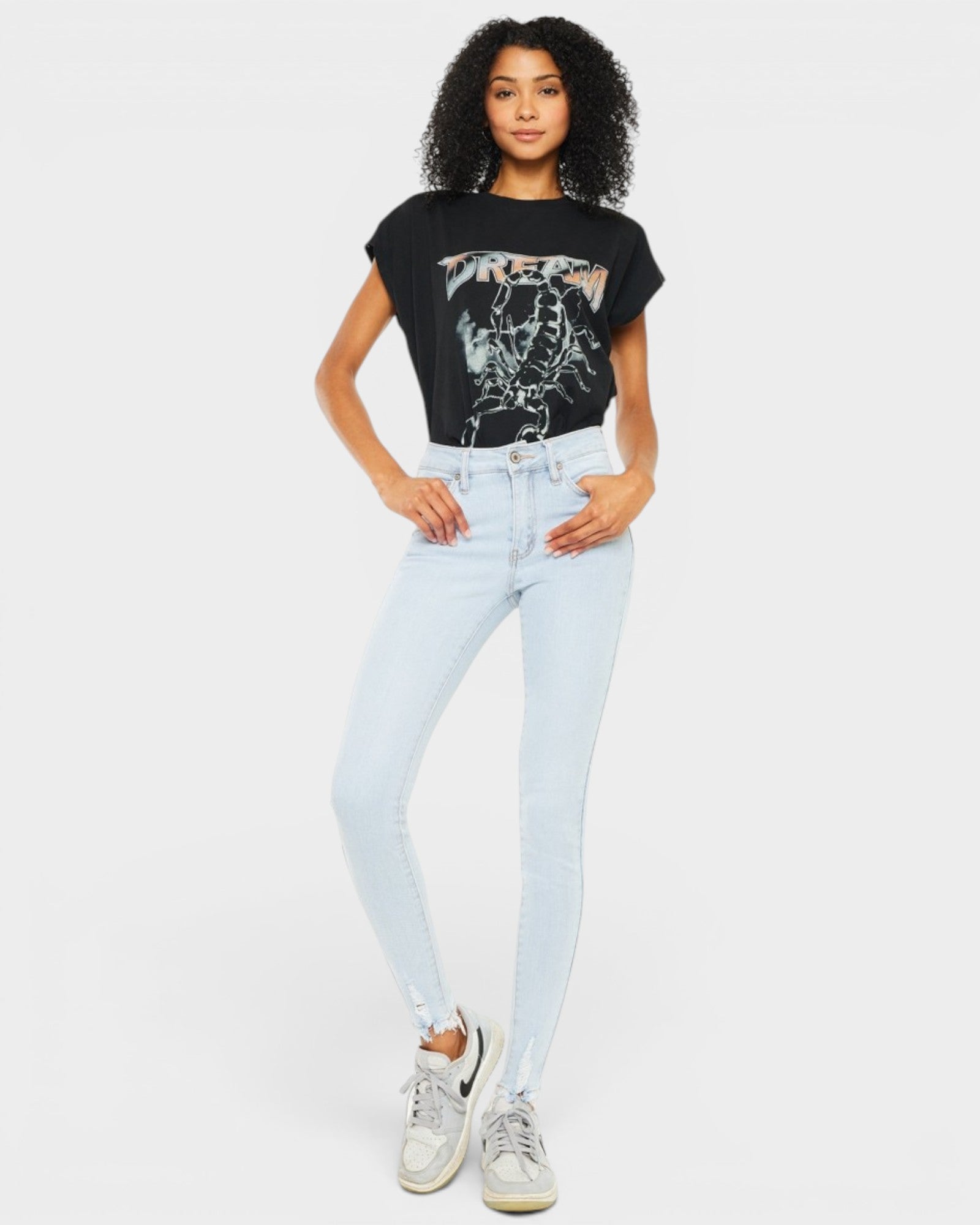 Woman wearing a black graphic t-shirt and light blue jeans on a white background