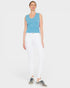 Woman wearing a blue sleeveless top and white pants on a white background